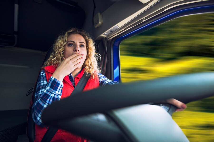 female-trucker-yawning-due-tiredness-boredom-while-driving-truck_342744-277